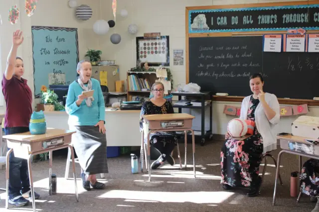 Students answering questions with desks positioned in circle
